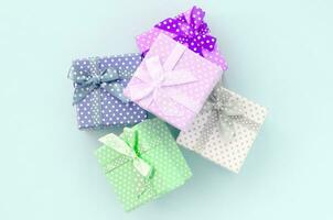 Pile of a small colored gift boxes with ribbons lies on a violet background. Minimalism flat lay top view photo