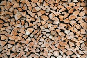 Firewood stacked near the wooden wall of old hut. Many chopped logs of firewood photo