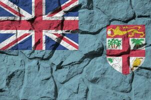 Fiji bandera representado en pintar colores en antiguo Roca pared de cerca. texturizado bandera en rock pared antecedentes foto