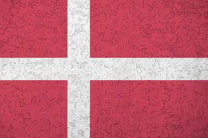 Denmark flag depicted in bright paint colors on old relief plastering wall. Textured banner on rough background photo