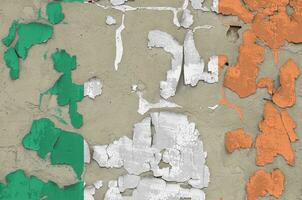 Ireland flag depicted in paint colors on old obsolete messy concrete wall closeup. Textured banner on rough background photo