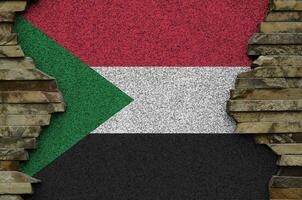 Sudan flag depicted in paint colors on old stone wall closeup. Textured banner on rock wall background photo