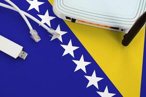 Bosnia and Herzegovina flag depicted on table with internet rj45 cable, wireless usb wifi adapter and router. Internet connection concept photo