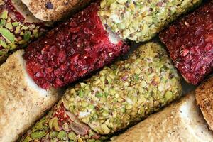 Rolls of turkish delight with many different flavors and fillings close up on table of vendors market photo