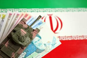 Iranian army toy tank drive on iranian bills of rial currency on flag of Islamic Republic of Iran photo