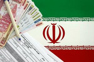 Iranian annual income tax return form F20-25-006 ready to fill on table with pen and iranian money on flag photo