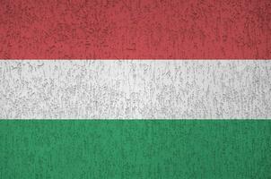 Hungary flag depicted in bright paint colors on old relief plastering wall. Textured banner on rough background photo