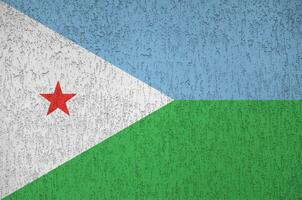 Djibouti flag depicted in bright paint colors on old relief plastering wall. Textured banner on rough background photo