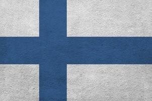 Finland flag depicted in bright paint colors on old relief plastering wall. Textured banner on rough background photo