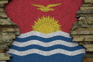 Kiribati flag depicted in paint colors on old stone wall closeup. Textured banner on rock wall background photo