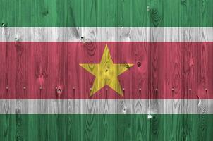 Suriname flag depicted in bright paint colors on old wooden wall. Textured banner on rough background photo