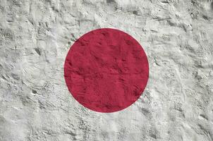 Japón bandera representado en brillante pintar colores en antiguo alivio enlucido pared. texturizado bandera en áspero antecedentes foto