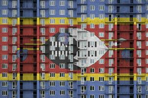 Swaziland flag depicted in paint colors on multi-storey residental building under construction. Textured banner on brick wall background photo