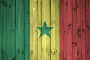 Senegal bandera representado en brillante pintar colores en antiguo de madera pared. texturizado bandera en áspero antecedentes foto