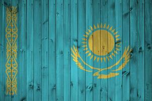 Kazakhstan flag depicted in bright paint colors on old wooden wall. Textured banner on rough background photo
