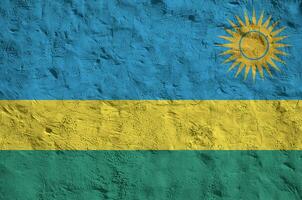 Rwanda flag depicted in bright paint colors on old relief plastering wall. Textured banner on rough background photo