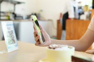 Woman use smartphone to scan QR code to pay in cafe restaurant with a digital payment without cash. Choose menu and order accumulate discount. E wallet, technology, pay online, credit card, bank app. photo