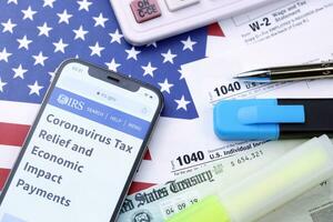 KHARKOV, UKRAINE - MARCH 5, 2021 Official IRS website with 1040 and w-2 paper tax forms on US flag photo