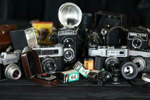 KHARKOV, UKRAINE - APRIL 27, 2021 Film photo cameras and another old retro photo equipment on black wooden table in photographer darkroom. Photographic gear from soviet union