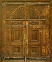 Very old solid wooden door in retro 19th century design close up photo