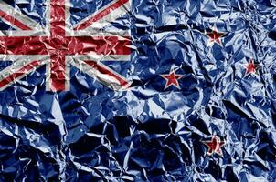 New Zealand flag depicted in paint colors on shiny crumpled aluminium foil closeup. Textured banner on rough background photo