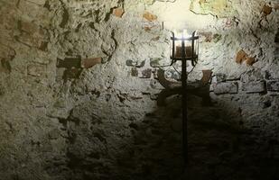 Lighted medieval castle torch hanging on a stone wall, vintage objects photo