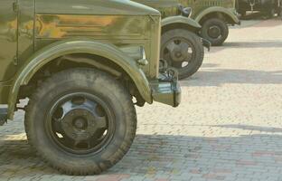 Photo of the cabins of three military off-road vehicles from the times of the Soviet Union. Side view of military cars from the front wheel