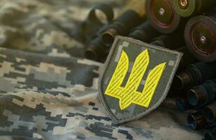 Ukrainian army symbol on machine gun belt lies on ukrainian pixeled military camouflage photo