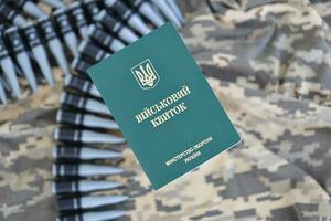 Ukrainian military ID on fabric with texture of pixeled camouflage. Cloth with camo pattern in grey, brown and green pixel shapes with Ukrainian army personal token photo