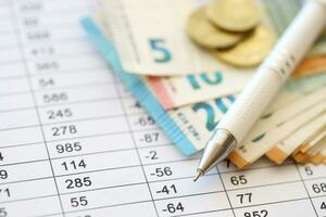 Business concept with many euro money bills and pen on schedules with calculations photo