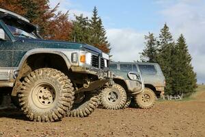 Automobile in a countryside landscape with a mud road. Off-road 4x4 suv automobile with ditry body after drive in muddy road photo