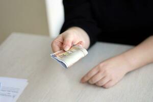 Brazilian money bills in woman hand. Female gives bunch of brazilian reais to us photo