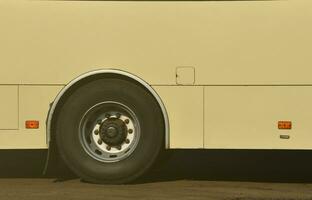 Photo of the hull of a large and long yellow bus with free space for advertising. Close-up side view of a passenger vehicle for transportation and tourism