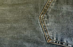 Detailed abstract texture of dark blue denim cloth. Background image of old used denim trousers fabric photo