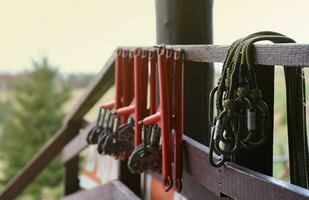 large metal locking carabiners with rope, climbing gear hanging on the store room. Height safety harness and arborist equipment photo