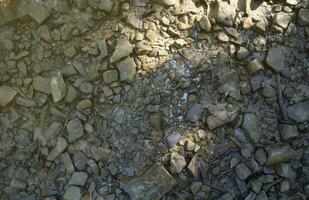 antecedentes de destrozado pedregoso piedras superficie en montaña área. textura con natural ligero foto