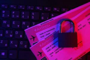 Fictional air tickets and small padlock on computer keyboard photo