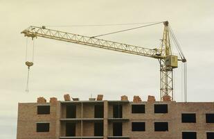 View of a large construction site with buildings under construction and multi-storey residential homes. Tower cranes in action on blue sky background. Housing renovation concept photo