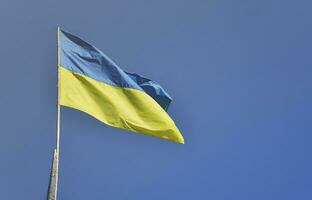 Ukrainian flag against the blue cloudless sky. The official flag of the Ukrainian state includes yellow and blue colors photo