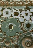 A composition of a set of gears and car parts that are welded to each other and painted green. Grunge steampunk texture photo