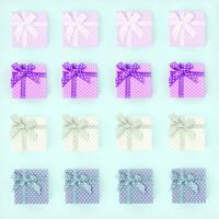 Piles of a small colored gift boxes with ribbons lies on a violet background. Minimalism flat lay top view pattern photo