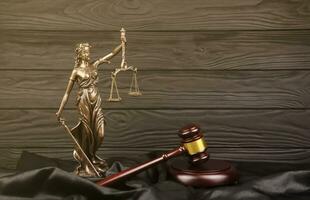 The Statue of Justice - lady justice or justitia the Roman goddess of Justice. Statue on brown book with judge gavel. Concept of judicial trial, courtroom process and lawyers work photo