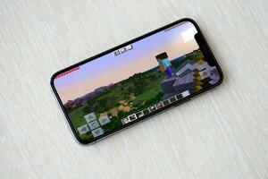 Minecraft mobile iOS game on smartphone screen on wooden table during mobile gameplay photo