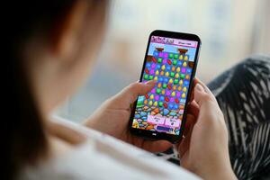 Candy Crush Saga mobile iOS game on iPhone 15 smartphone screen in female hands during mobile gameplay photo