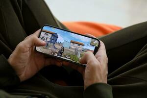 PUBG PlayerUnknowns Battlegrounds mobile iOS game on iPhone 15 smartphone screen in male hands during mobile gameplay photo