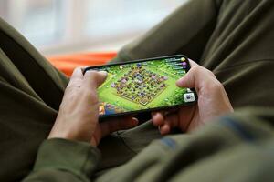 Clash of Clans mobile iOS game on iPhone 15 smartphone screen in male hands during mobile gameplay photo
