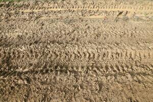 rueda pista en lodo. huellas de un tractor o pesado fuera del camino coche en marrón barro en mojado prado foto