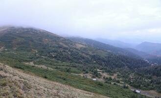 Morning view from the Dragobrat mountain peaks in Carpathian mountains, Ukraine. Cloudy and foggy landscape around Drahobrat Peaks photo