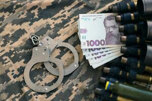 Ukrainian army machine gun belt shells and handcuffs on military uniform. Concept of bribery and war crimes photo