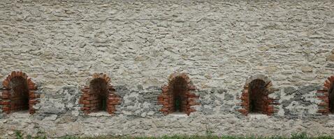 Very old window in brick stone wall of castle or fortress of 18th century. Full frame wall with window photo